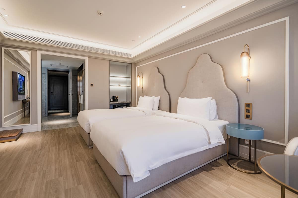 Una habitación de hotel con una cama grande, una mesita de noche, un espejo y un televisor.
