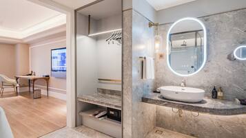 A modern bathroom with a marble countertop, a large mirror, and a shower area.