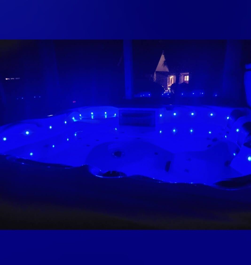 Un espace extérieur peu éclairé, avec une piscine et une maison en arrière-plan.