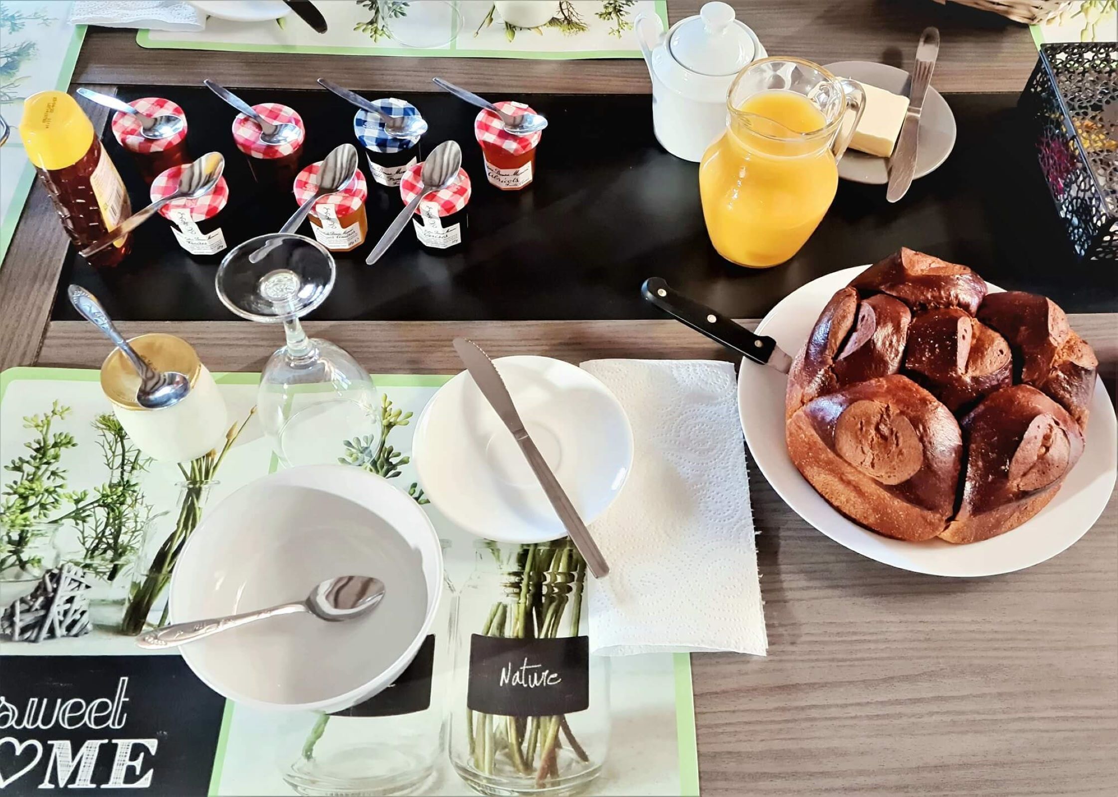 A breakfast setting with a variety of food items, including bread, condiments, and a glass of orange juice.