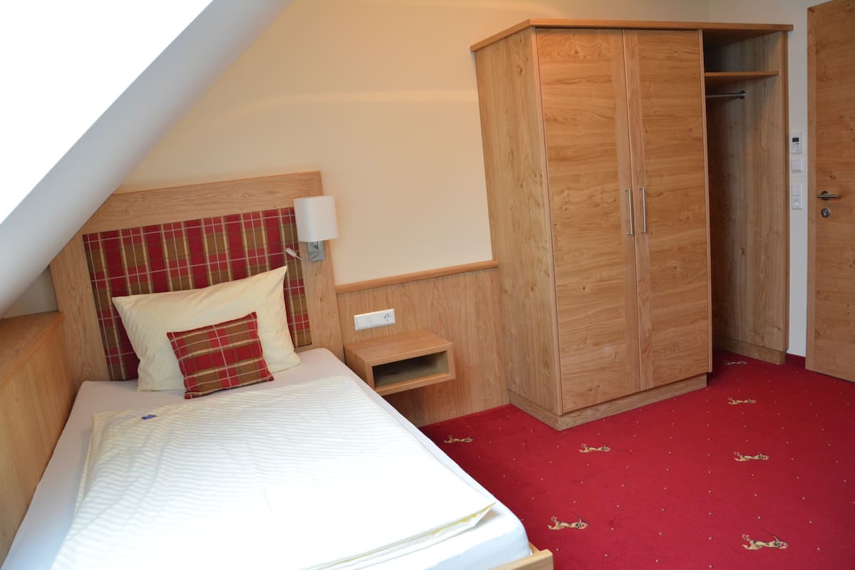 Ein Schlafzimmer mit einem Bett, einem Kleiderschrank, einem Nachttisch und einem roten Teppich.