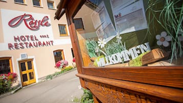 Un cartel de hotel con 'Rössle Hotel Restaurant' y un cartel de bienvenida con 'Willkommen' en primer plano.