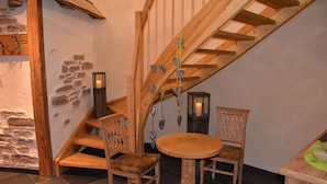 A wooden staircase with heart-shaped decorations, a round wooden table, and two chairs in a room with stone walls and a tiled floor. - Landgasthof Hotel Rössle (Boehmenkirch)