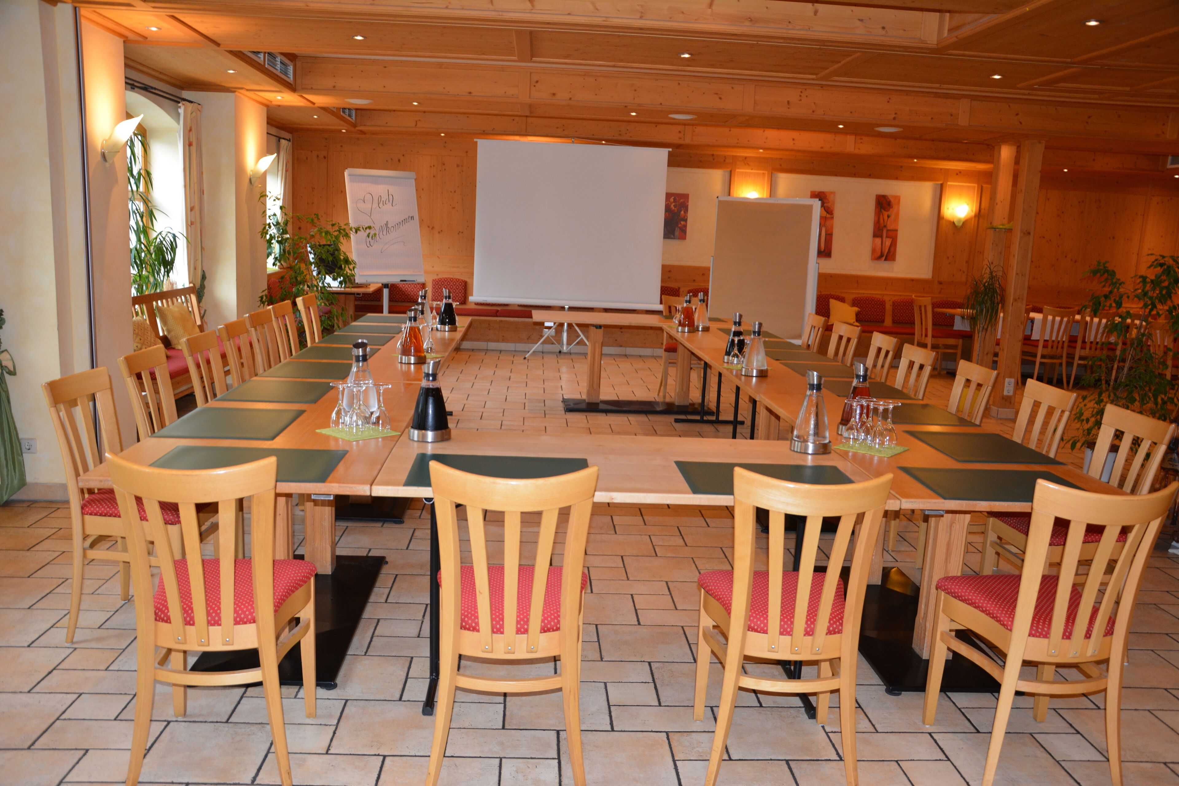 Une salle de conférence avec une longue table, des chaises, un tableau blanc et des plantes en pot.