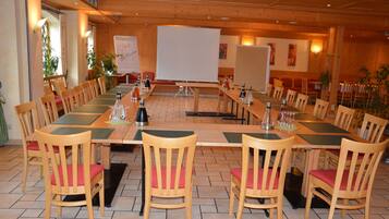 Une salle de conférence avec une longue table, des chaises, un tableau blanc et des plantes en pot.