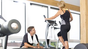 A gym with treadmills and weight machines, large windows, and a wooden ceiling. - Landgasthof Hotel Rössle (Boehmenkirch)