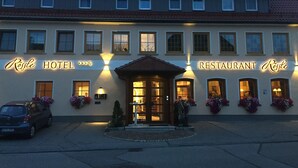 A hotel and restaurant with a tiled roof, multiple windows, and illuminated signage. - Landgasthof Hotel Rössle (Boehmenkirch)