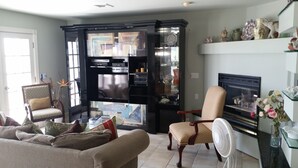 A living room with a fireplace, a television, and a bookshelf. - NEW LISTING! Beachfront Villa (Manasquan)