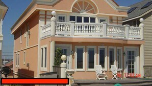 A two-story house with a balcony, a front porch with chairs, and a small fountain. - NEW LISTING! Beachfront Villa (Manasquan)