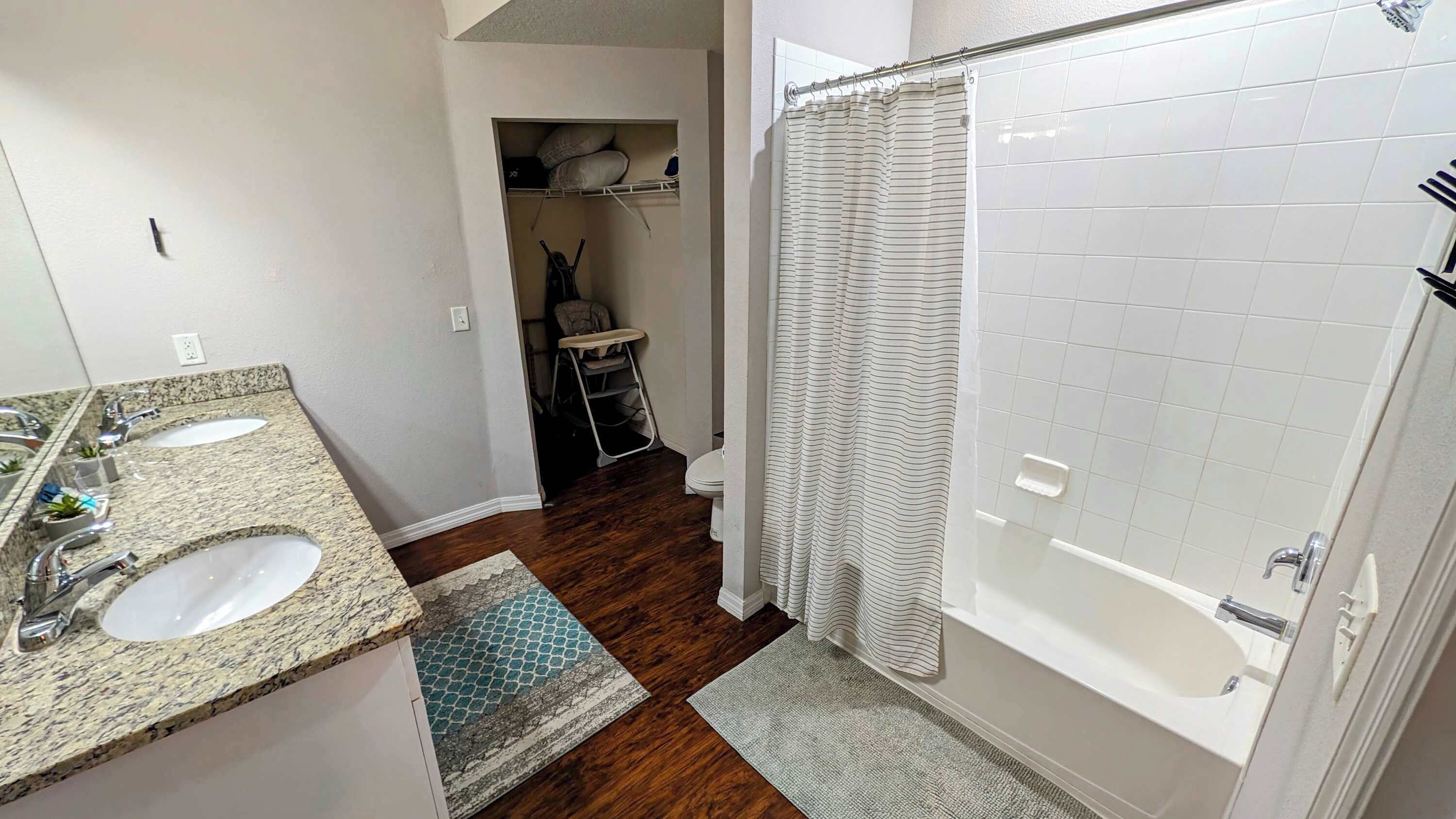A bathroom with a double sink, a shower, and a toilet.