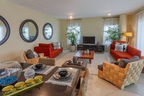 A living room with a sofa set, a coffee table, a TV, and a dining area with a table and chairs.
