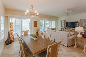 A spacious living area with a dining table, chairs, a sofa, and a television.