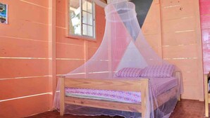Un dormitorio con cama de madera, una ventana y mosquitero.