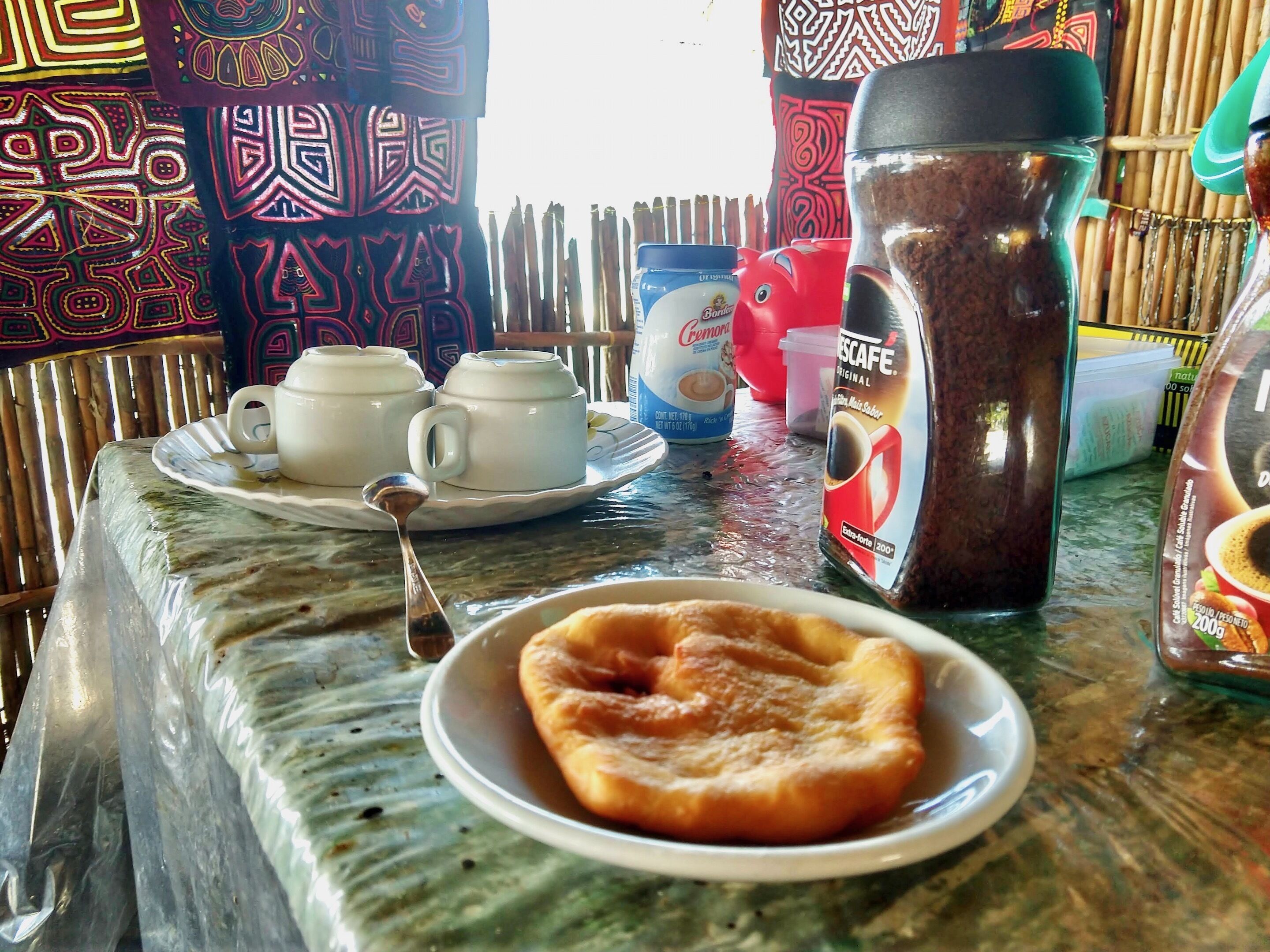 Una mesa con un plato de comida, una cafetera y una taza de café.