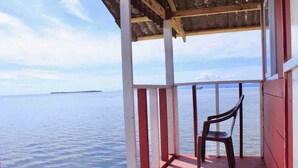 Un espacio al aire libre techado con un banco de madera y vista al agua.