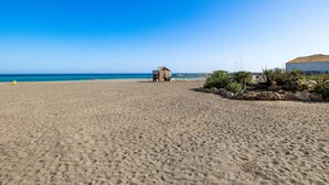 Una playa con una cabaña pequeña, cielo azul despejado y mar tranquilo.