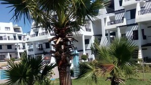 Un edificio moderno con varios balcones y una zona de piscina.