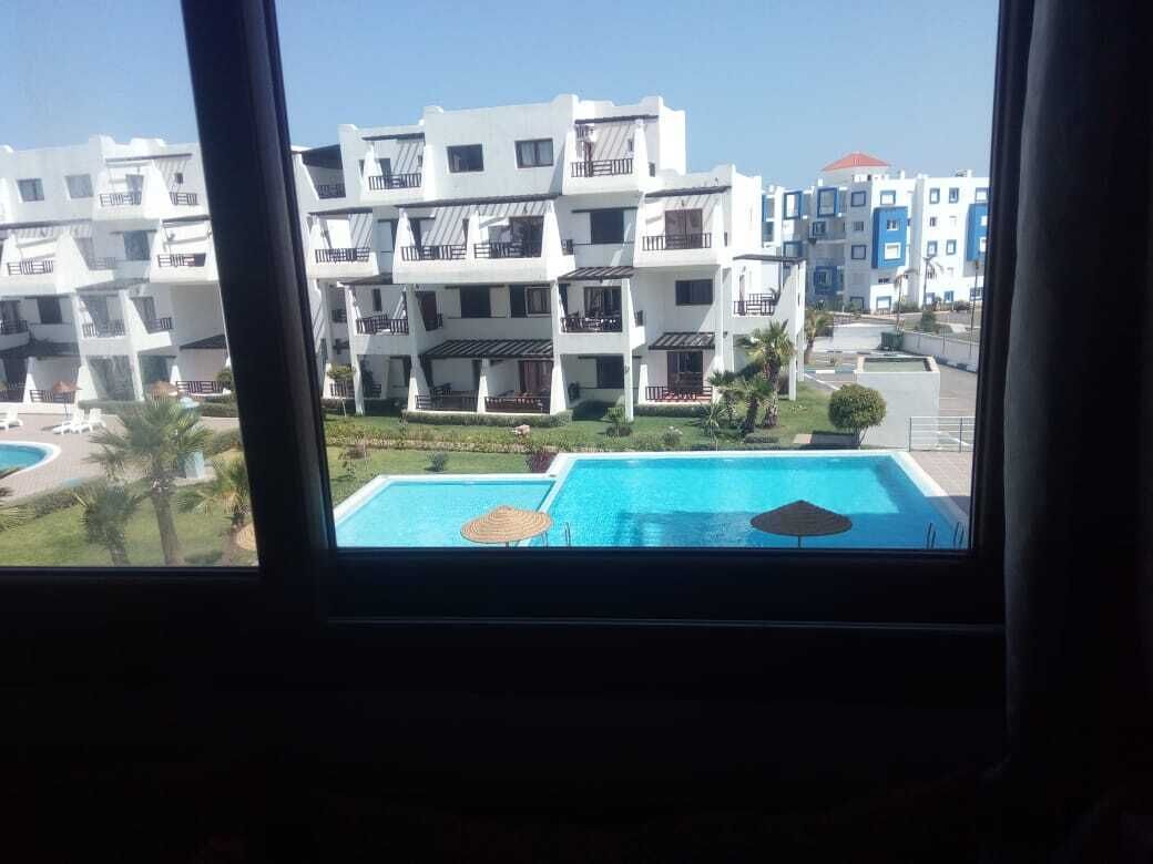 Vista di un edificio moderno con numerosi balconi e una piscina in primo piano.