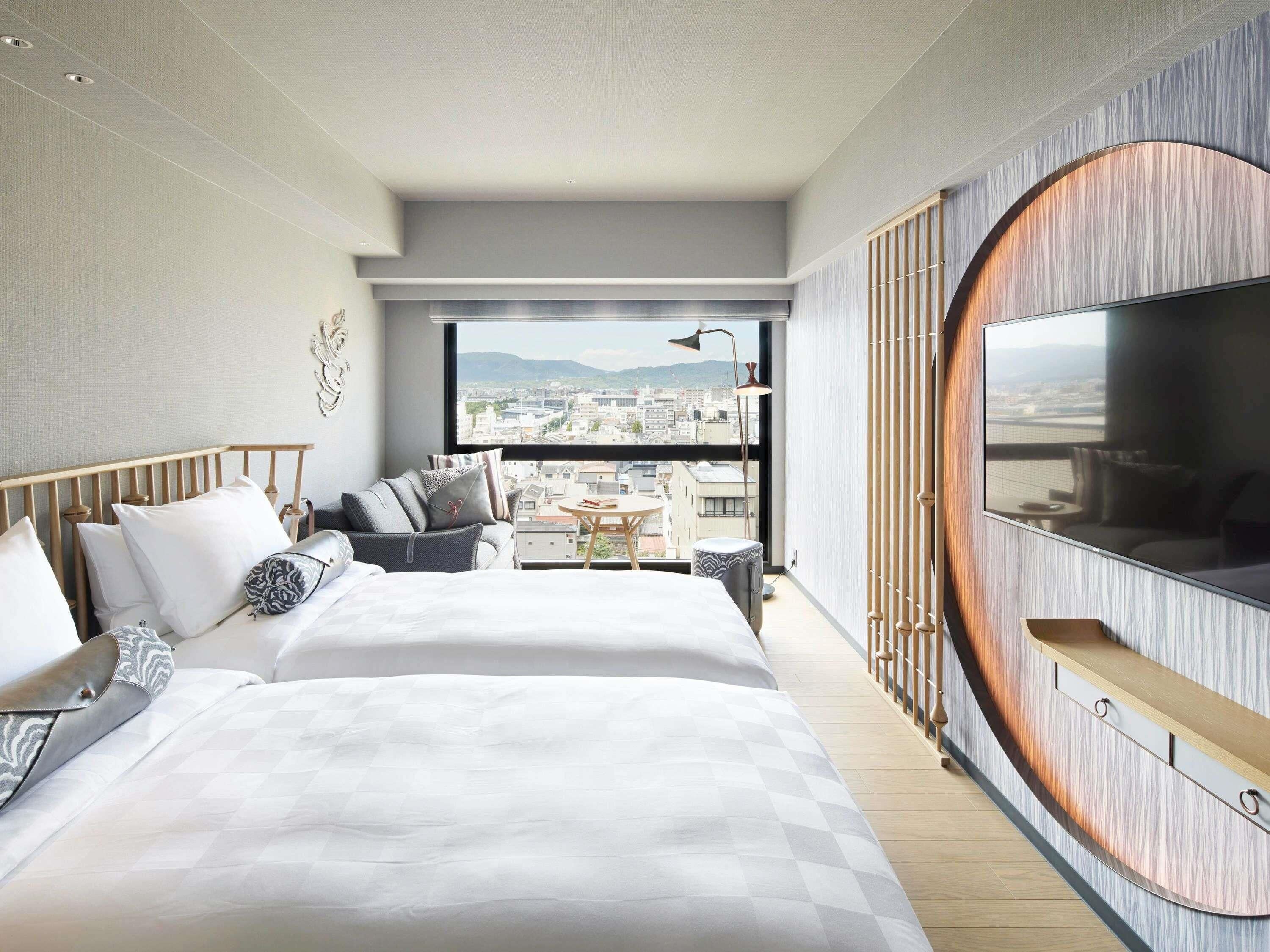 Une chambre d’hôtel moderne dotée d’un grand lit, d’un coin salon avec vue et d’un téléviseur fixé au mur.