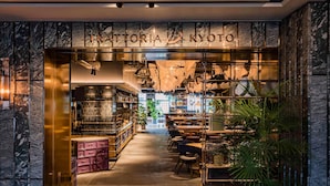Un interior de restaurante moderno con una pared de mármol, una zona de bar central y diferentes distribuciones de mesas.