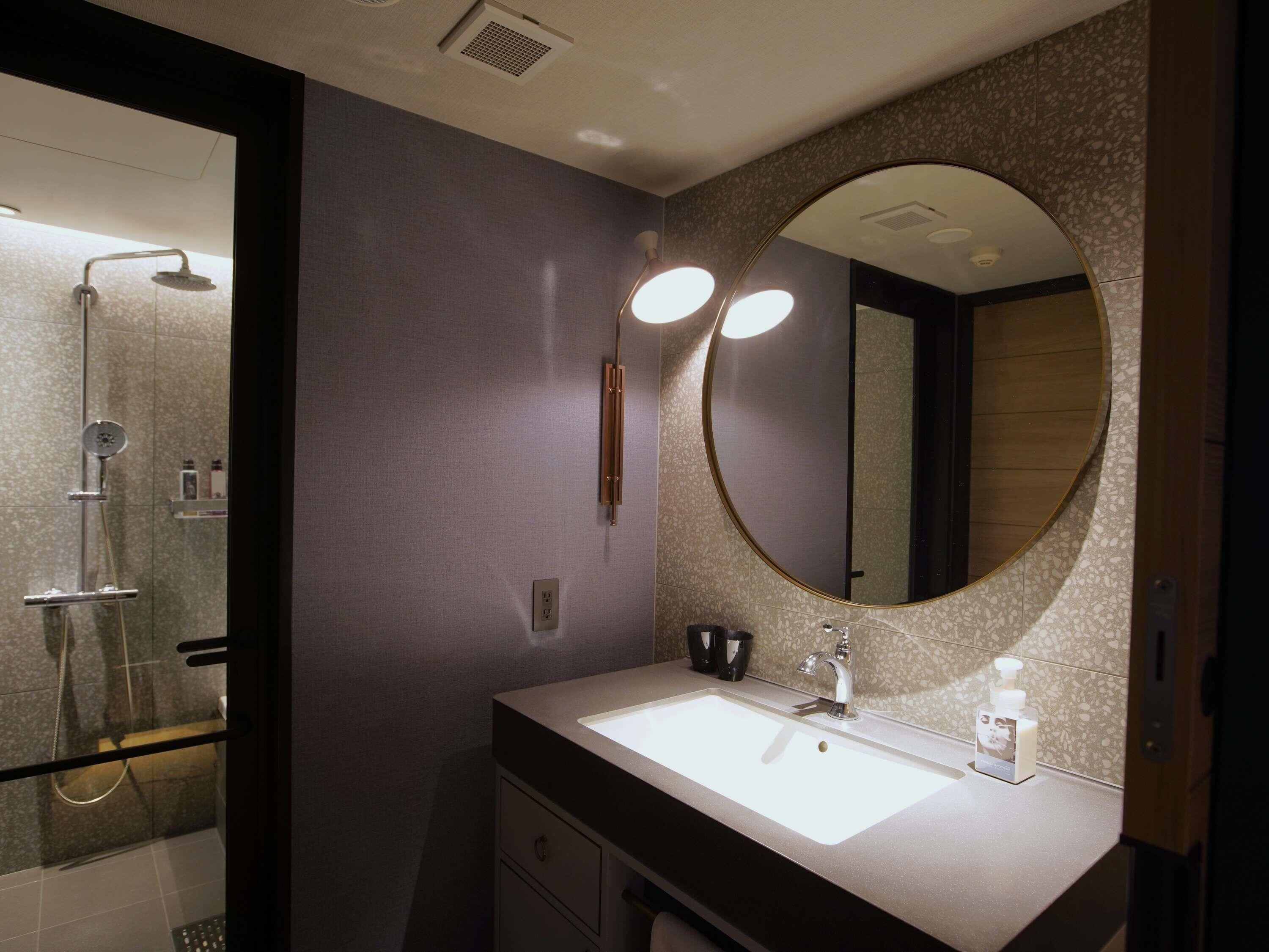 Un baño moderno con un espejo grande, un lavabo y una ducha.