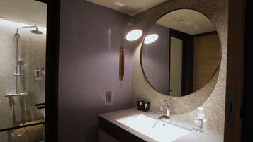 Un baño moderno con un espejo grande, un lavabo y una ducha.