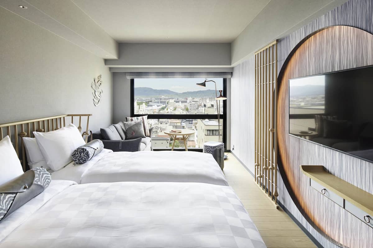 Habitación de hotel moderna con una cama grande, televisión, balcón con vista a la ciudad y una pared de acento de madera.