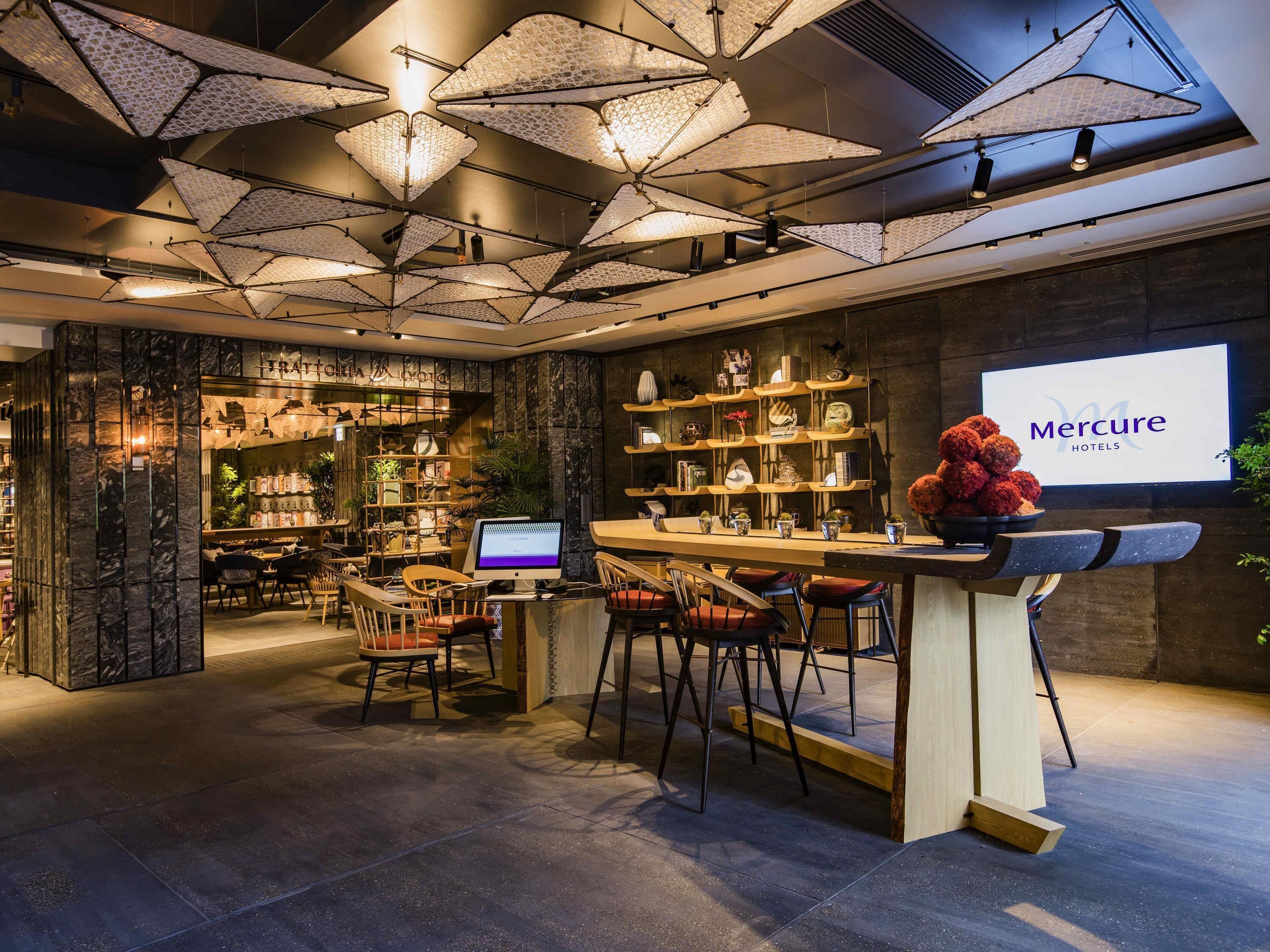 A bar area with a digital screen, seating, and a display of Mercure Hotels.