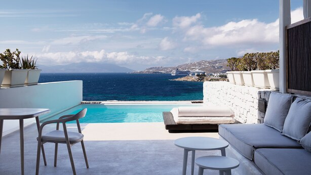 A modern outdoor seating area with a pool, overlooking the sea and a distant island. - Mykonos Earth Suites - Adults Only (Mykonos)