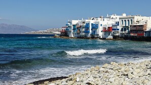A coastal town with white buildings with blue accents, a rocky shoreline, and the sea. - Mykonos Earth Suites - Adults Only (Mykonos)