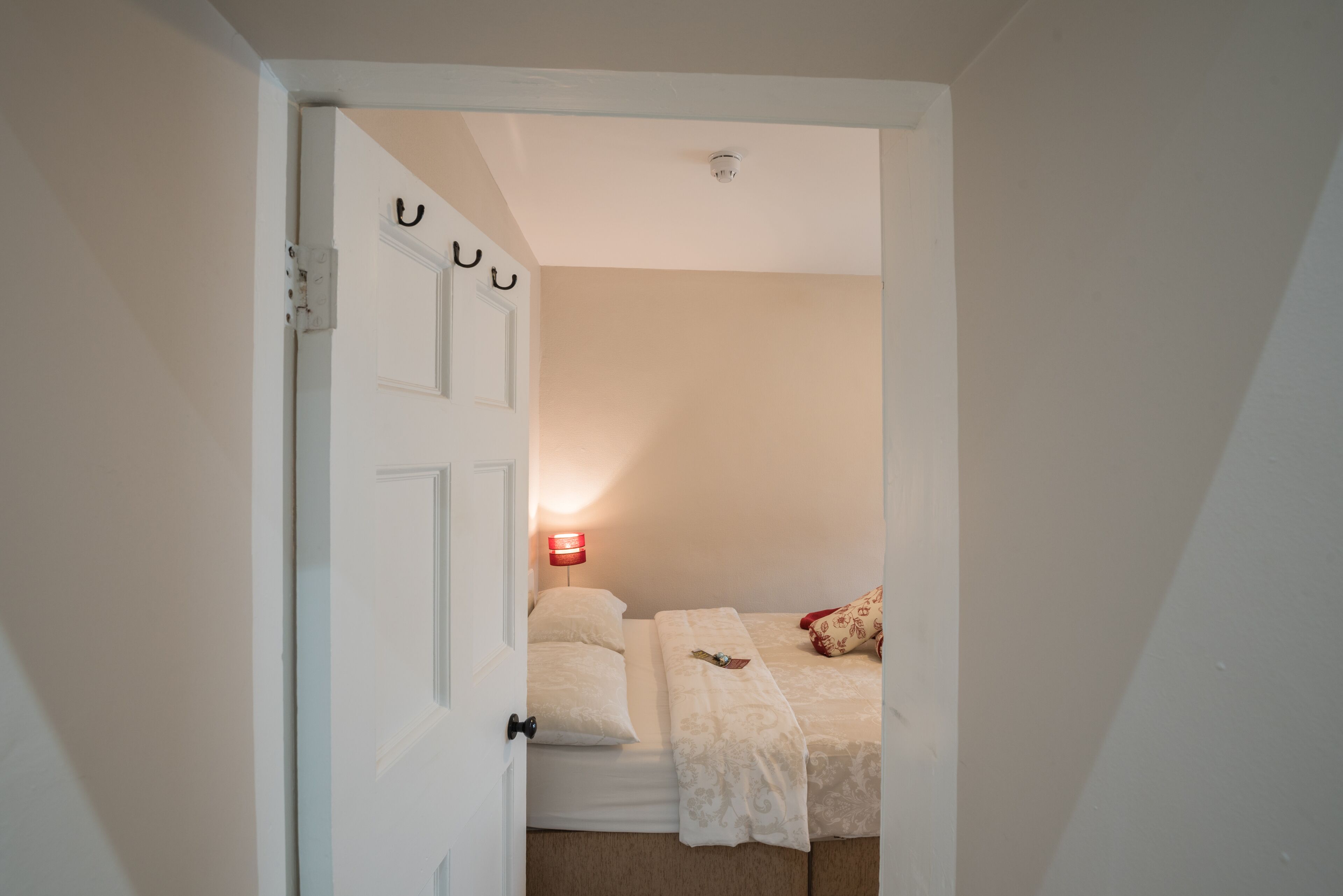 A bedroom with two beds, a bedside lamp, and a wall-mounted light fixture.