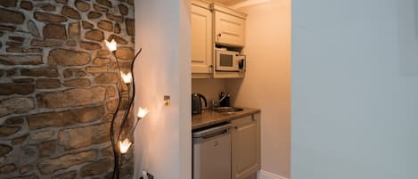 A kitchen with a stone wall, a built-in microwave, and a dishwasher.