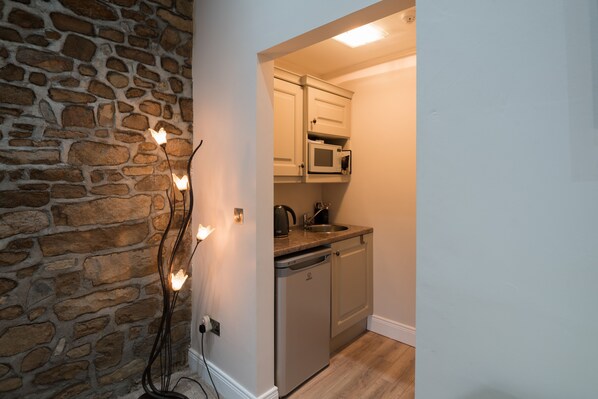 A kitchen with a stone wall, a built-in microwave, and a dishwasher.