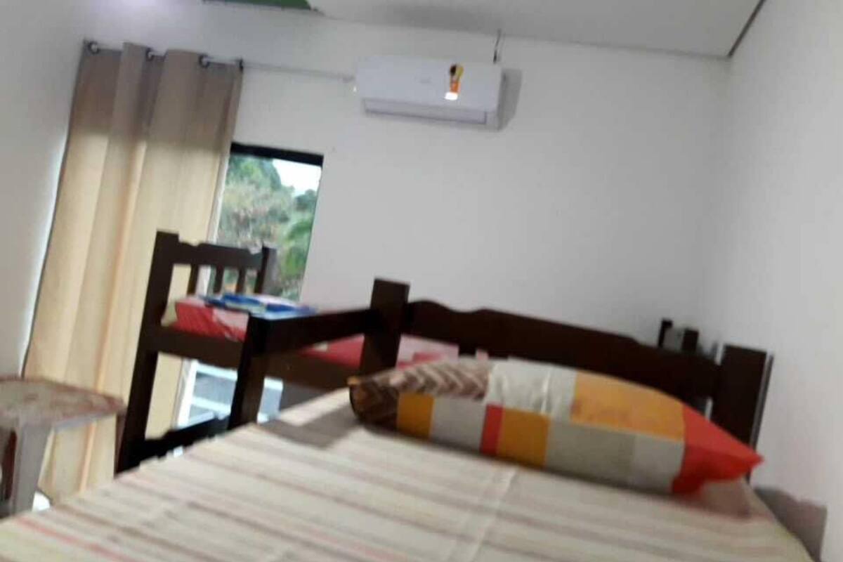 Ein Schlafzimmer mit einem Bett, einem Fenster mit Vorhängen und einer Klimaanlage an der Wand.
