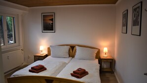 Un lit double avec deux oreillers, deux lampes de chevet et deux serviettes pliées posées sur le lit.