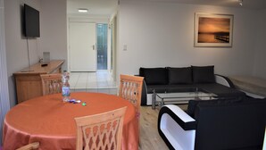 Un salon avec une table ronde, un canapé et un téléviseur fixé au mur.