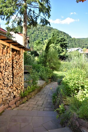 A stone pathway leading to a wooden structure with stacked firewood. - FVH Family Vacation Heidelberg (Heidelberg)