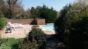 A swimming pool with a brick wall and lounge chairs.
