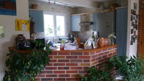 A kitchen with a brick counter, a coffee maker, and various kitchen items.