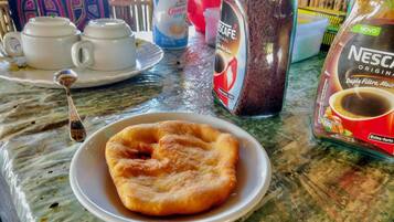 A breakfast setting with a plate of pastries, a coffee maker, and a Nescafé coffee packet.
