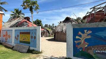Un pueblo rural con casas de techo de paja, un camino de tierra y un mural que representa la cultura local.