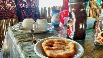 A table with a plate of food, a coffee pot, and a cup of coffee.