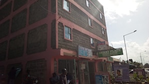 A multi-story building with signs for 'Kitui Software', 'Merry Place Guest House Conference Hall', and 'VIP Barbers'. - Merybyplace Guest House (Kitui)