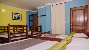 Een hotelkamer met twee enkele bedden, een houten hoofdeinde, een groot raam met gordijnen en een deur.