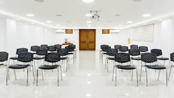 A conference room with rows of black chairs, a projector, and a wooden door.