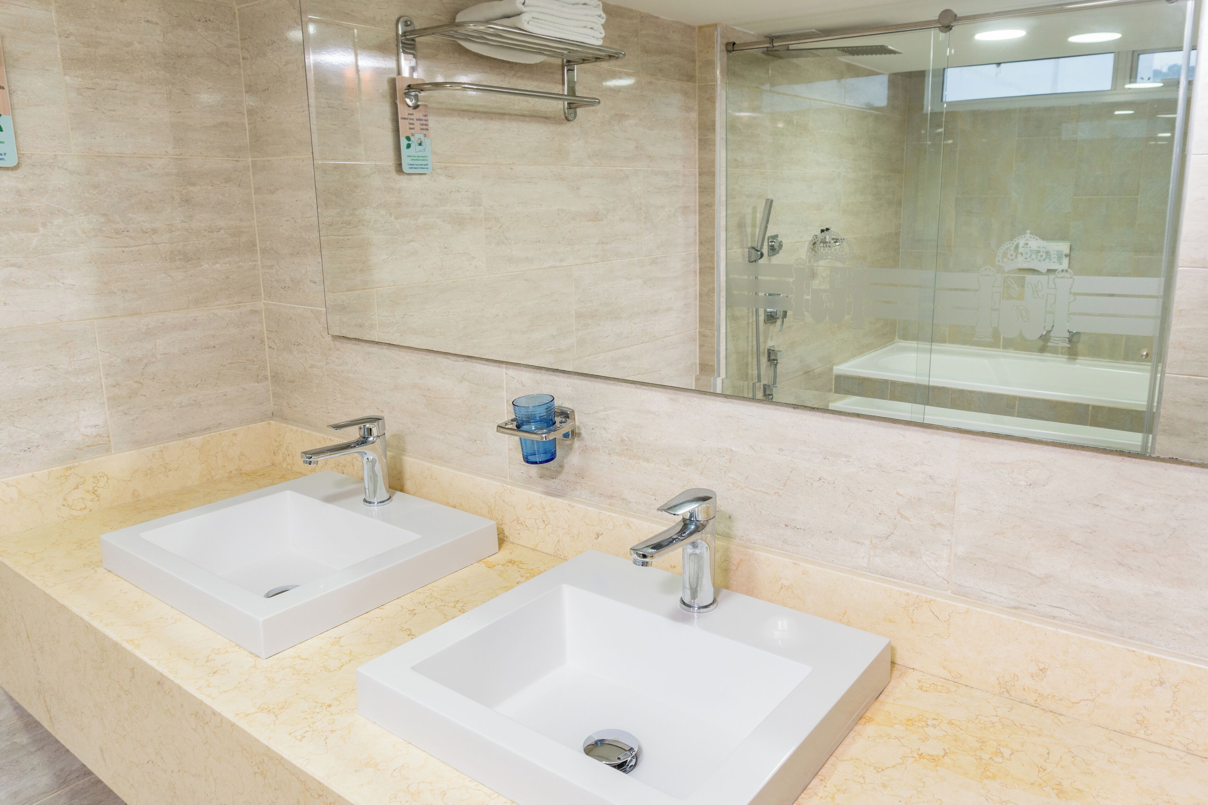 A modern bathroom with two white sinks, a glass shower enclosure, and a large mirror.