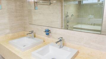 A modern bathroom with two white sinks, a glass shower enclosure, and a large mirror.