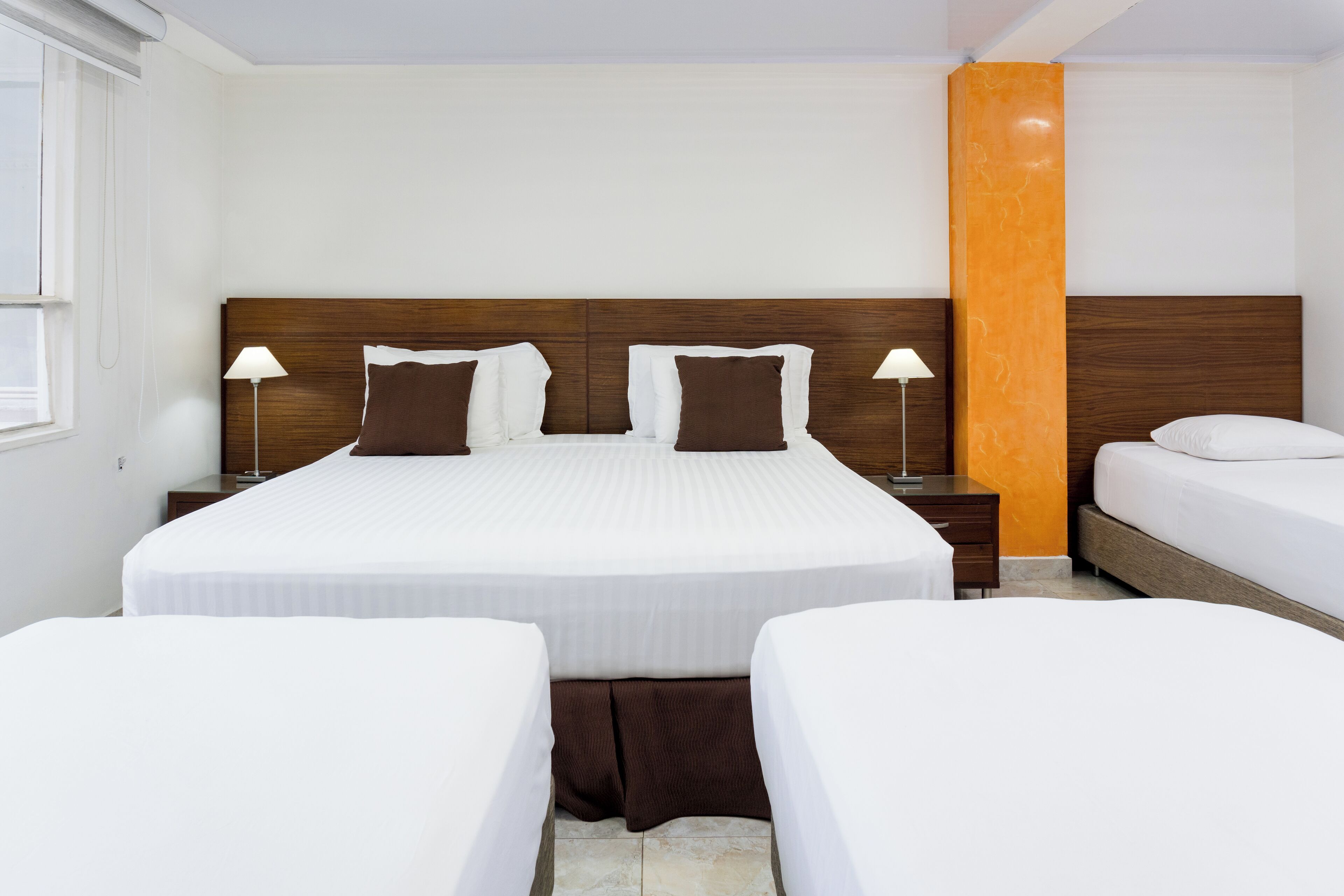 Een hotelkamer met een groot bed, twee nachtkastjes en een raam.