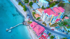 An aerial view of a coastal hotel with multiple buildings, a beach, and a pier. - Cane Garden Bay Beach Hotel (Cane Garden Bay)