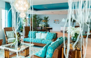 A spacious living room with a blue ceiling, a large sofa, and a dining area with a table and chairs. - Cane Garden Bay Beach Hotel (Cane Garden Bay)
